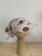 Wzór, który przyciąga wzrok! Zbliżenie na detale tkaniny muślinowej – piłki w różnych stylach na delikatnym beżu. Bezpiecznie, miękko, naturalnie.