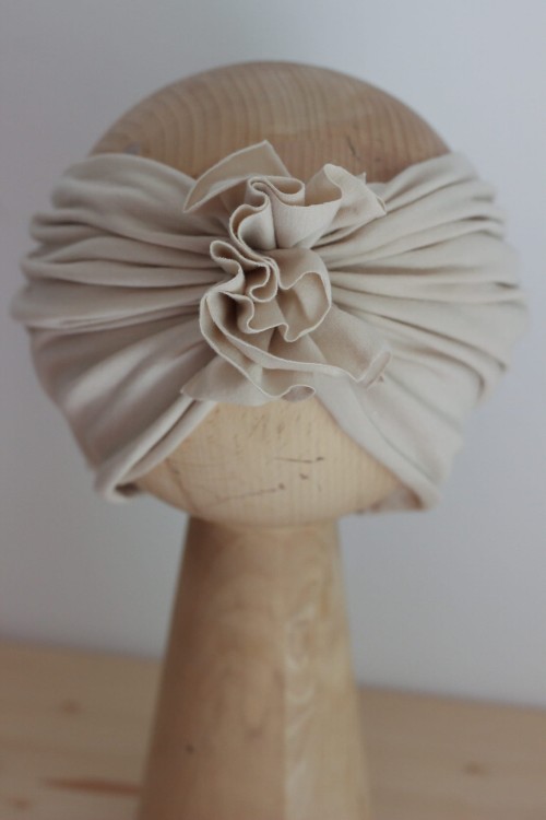 Opaska turbanowa w kolorze jasny beż – delikatna i uniwersalna. Idealna dla małych dziewczynek na co dzień i na specjalne okazje. Subtelny kolor pasuje do każdej stylizacji.