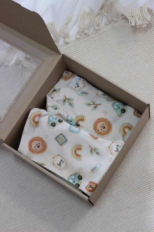 Zestaw prezentowy dla chłopca zapakowany w eleganckie pudełko z okienkiem – body i legginsy w urocze ciasteczka na beżowym tle. Gotowy do wręczenia na baby shower lub urodziny.