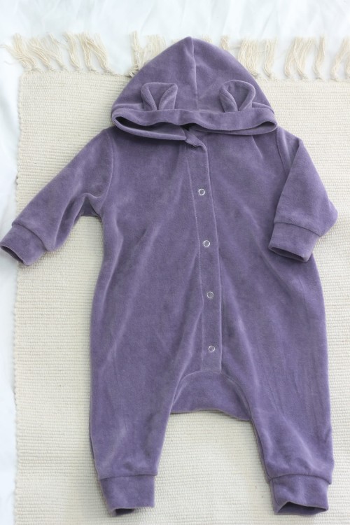 Lawendowy kombinezon niemowlęcy z bawełnianego weluru w pełnej okazałości – widać jego prosty, wygodny krój oraz miękki materiał, który idealnie otula maluszka.